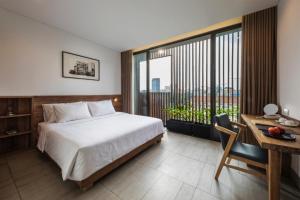 a bedroom with a bed and a desk and a window at Triple E Hotel Fine Art Museum in Ho Chi Minh City