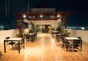 un restaurante con mesas y sillas en un balcón por la noche en Nichols Airport Hotel en Manila