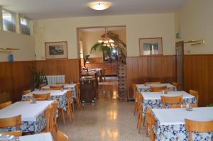 a dining room with white tables and wooden chairs at Albergo Padellino in Vaglia