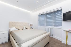 a white bedroom with a bed and a window at TA House in Edgware