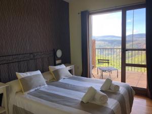 a bedroom with a bed and a balcony with a view at Hotel Rural Porta Coeli - Dehesa Santa Lucía in San Martín del Castañar +68 photos