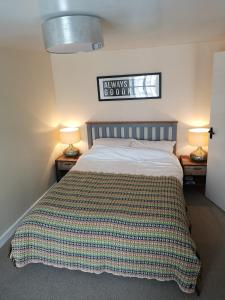 a bedroom with a bed with a striped blanket on it at Ty Isa in Nefyn