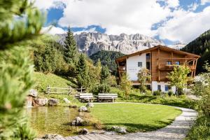 a house in the mountains next to a pond at Boutique Hotel Nives - Luxury & Design in the Dolomites in Selva di Val Gardena