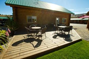 a wooden deck with a table and chairs in front of a cabin at Cody Cowboy Village in Cody