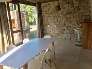 una mesa y sillas en una habitación con una pared de piedra en Tila Playa en Las Gaviotas