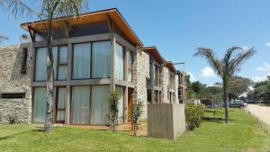 una casa con grandes ventanas de cristal y árboles en Tila Playa en Las Gaviotas