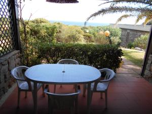 a table and chairs on a patio with a view of the ocean at Le Case Punta Negra in Stintino +28 photos