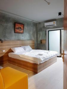 een slaapkamer met een groot bed en een gele kruk bij Sands Place Apartment and Hotel in Samut Sakhon