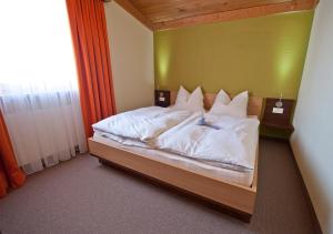 1 dormitorio con 1 cama con sábanas y almohadas blancas en Apartment Bergsonne, en Samnaun