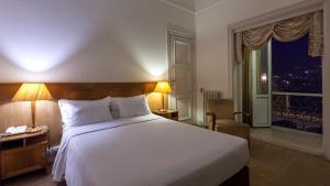 Un dormitorio con una gran cama blanca y una ventana en Hotel Astoria, en Coímbra