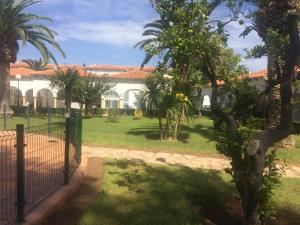 une clôture devant un bâtiment avec des palmiers dans l'établissement Casas Blancas Bungalow 45, à L'Alfàs del Pi