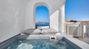 - une piscine avec deux oreillers dans une chambre blanche dans l'établissement Amaya Selection of Villas, à Oia