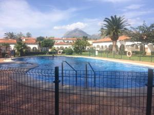 une piscine avec une clôture en face d'un bâtiment dans l'établissement Casas Blancas Bungalow 45, à L'Alfàs del Pi