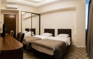 モスクワにあるVishnevyy Sad Hotelのベッド3台とデスクが備わるホテルルームです。