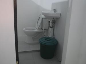 a bathroom with a toilet and a sink and a trash can at Sunset Beach House in Matnog