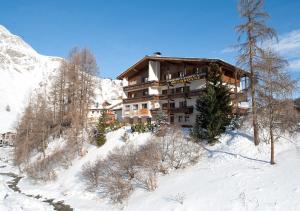 ein Gebäude auf einem verschneiten Hügel mit Bäumen und Schnee in der Unterkunft Hotel Garni Bergsonne in Samnaun