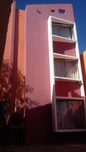 Hotel Don Alfredo في كالاما: مبنى وردي وبيضاء مع الكثير من النوافذ