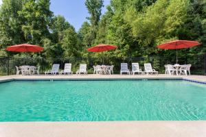 a pool with tables and chairs and umbrellas at Microtel Inn & Suites by Wyndham Lillington/Campbell University in Lillington