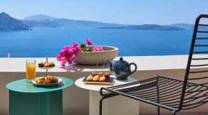 a table with a plate of fruit and a drink at Amaya Selection of Villas in Oia