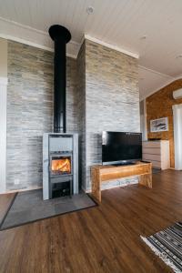 a living room with a fireplace and a tv at Jokiniemen Matkailu Cottages in Tölvä