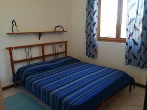 1 dormitorio con 1 cama con manta de rayas azules en Casa Poli, en Isola Rossa