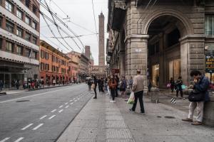 a group of people walking down a city street at San Petronio Central Studio in Bologna