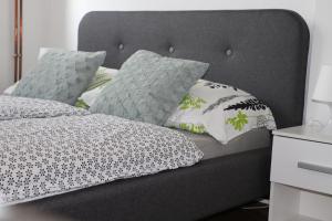 een bed met een grijs hoofdeinde met kussens erop bij Apartment Dunav in Osijek