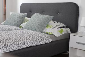 1 cama con cabecero gris y almohadas en Apartman Dunav - PARKING - Self check in, en Osijek
