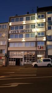 City Hotel Wuppertal في فوبرتال: سيارة بيضاء متوقفة أمام فندق المدينة