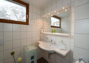 a white bathroom with a sink and a mirror at Apart Primavera in Samnaun +10 photos