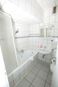 a white bathroom with a tub and a sink at City Hotel Wuppertal in Wuppertal