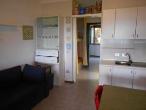 a living room with a couch and a kitchen at Le Case Punta Negra in Stintino