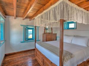 a bedroom with a canopy bed and two windows at Eirini Luxury Hotel Villas in Grikos +37 photos
