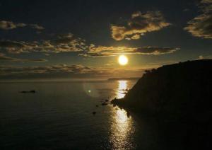 um pôr-do-sol sobre o oceano com o sol no céu em Las Golondrinas em Casiellas