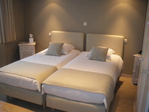 a bedroom with two beds with white sheets and pillows at Hotel Amaryllis in Maldegem