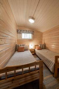 a bedroom with two beds in a log cabin at Jokiniemen Matkailu Cottages in Tölvä