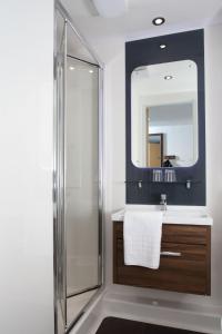 ein Bad mit einer Dusche, einem Waschbecken und einem Spiegel in der Unterkunft Sunley Hotel in Northampton