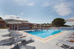 a swimming pool with lounge chairs and umbrellas at Remetzo Village in Lixouri