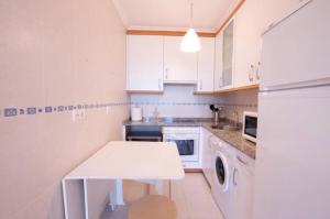 a kitchen with white cabinets and a white table at La Casa de Leo " only adults " in Muros de Nalón