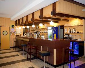 a bar in a restaurant with a man behind the counter at Hotel Belledonne in Le Bourg-dʼOisans