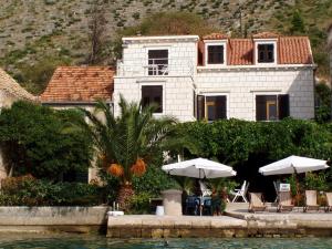 a house with tables and umbrellas in front of it at Villa Kukuljica in Zaton