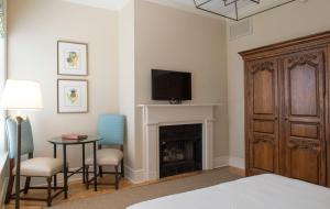 ein Schlafzimmer mit einem Bett, einem Kamin und einem TV in der Unterkunft Kings Courtyard Inn in Charleston