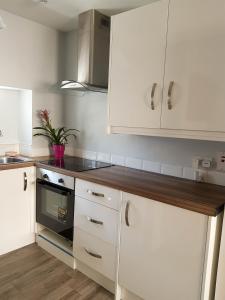 a kitchen with white cabinets and a stove top oven at Townhouse in Centre of Cobh in Cobh