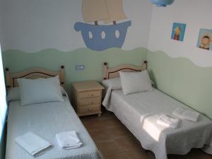 埃爾博斯克的住宿－ÁTICO CAHI，一间卧室配有两张床和一个带毛巾的床头柜。