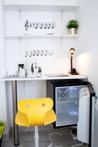 a kitchen with a yellow stool in front of a microwave at Comfortable rooms in Poznań