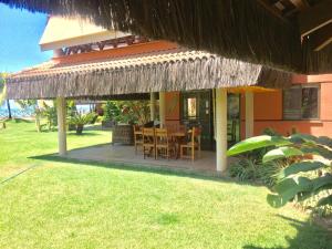a house with a dining table and a straw roof at Dream Village Cumbuco Beach in Cumbuco