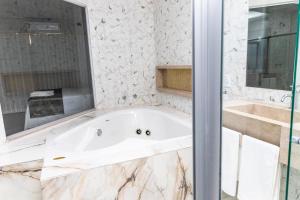 a white bathroom with a tub and a sink at Vila Real Hotel in Porto Nacional +38 photos