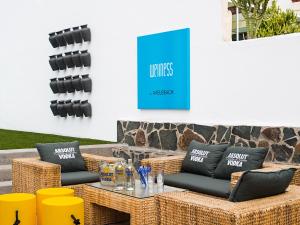 a patio with wicker furniture and a blue sign at AxelBeach Maspalomas - Apartments and Lounge Club - Adults Only in Playa del Ingles