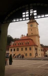 ブラショヴにある4 Rooms Piata Sfatuluiの時計塔が前に建つ建物