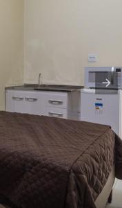 a bedroom with a bed and a kitchen with a sink at BH EXPO SUITES & KITNETES in Belo Horizonte